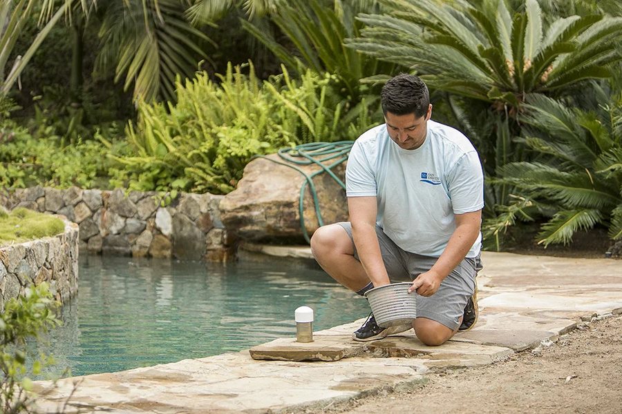 Technician skimming a pool on weekly service in Fontana